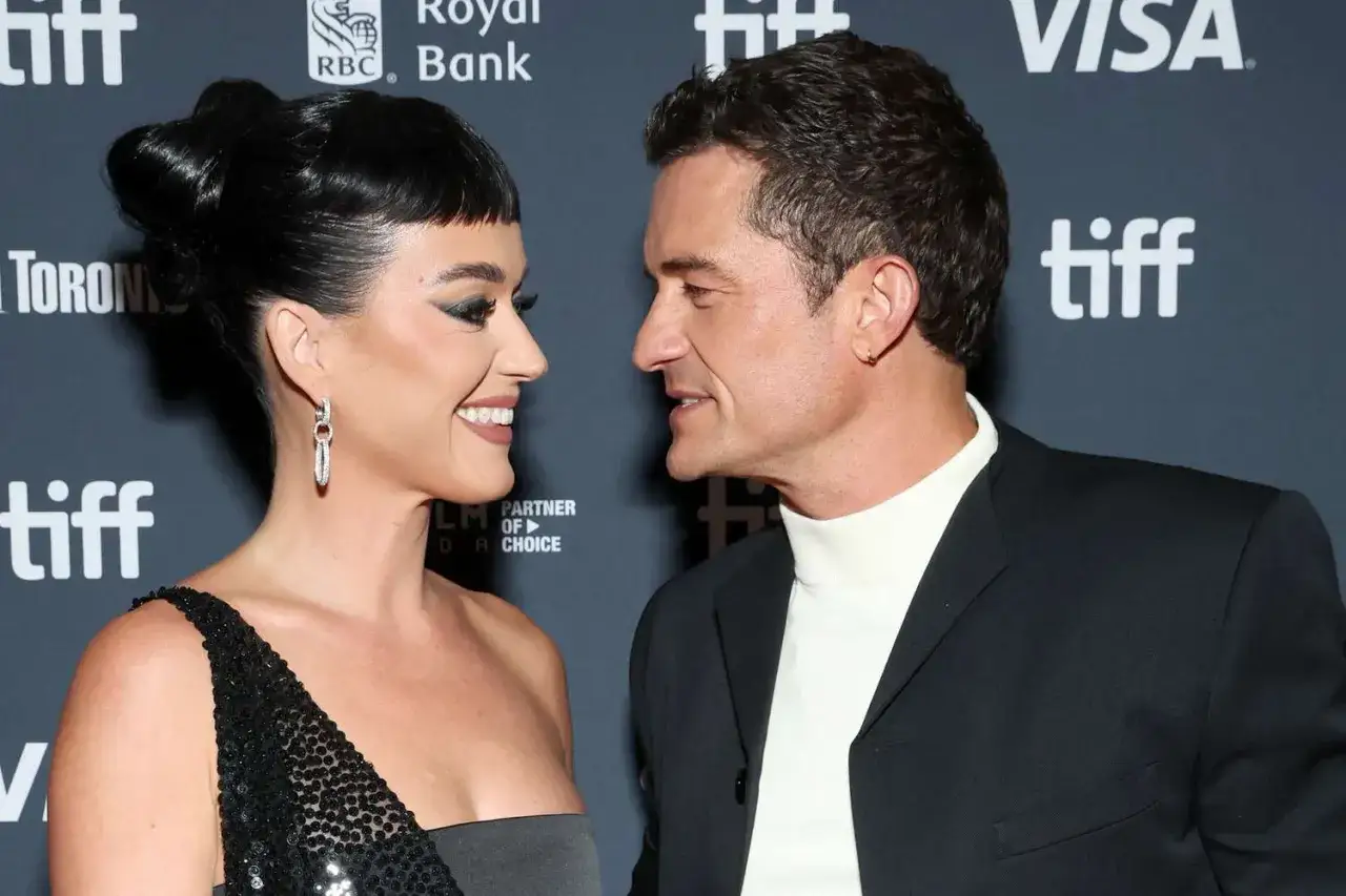 Orlando Bloom i Katy Perry patrzą na siebie z uśmiechem na tle logo TIFF.