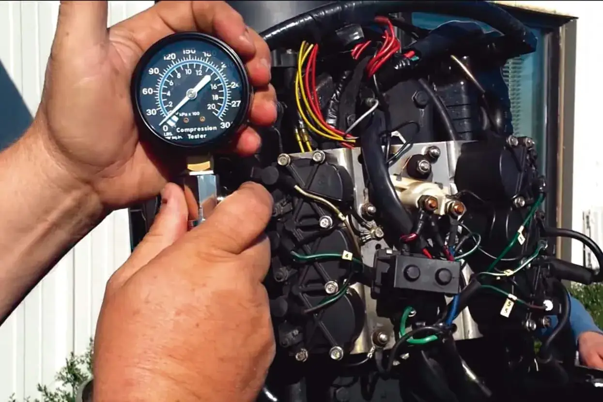 Mains d'un mécanicien testant la compression d'un moteur hors-bord. Le moteur se lance mais ne démarre pas essence.