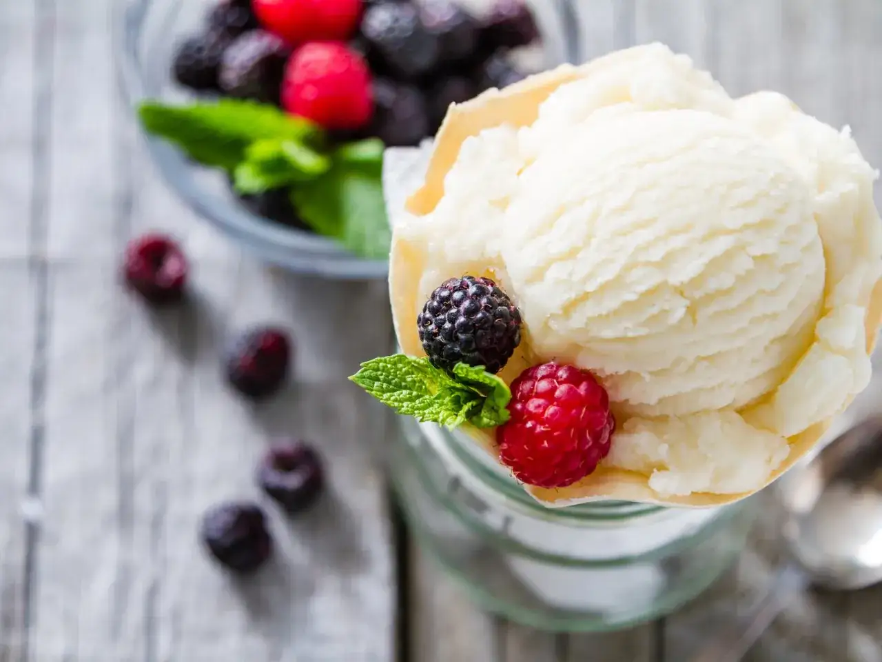Cremiges Joghurteis selber machen, garniert mit frischen Beeren und Minze. Ein Genuss für heiße Tage!
