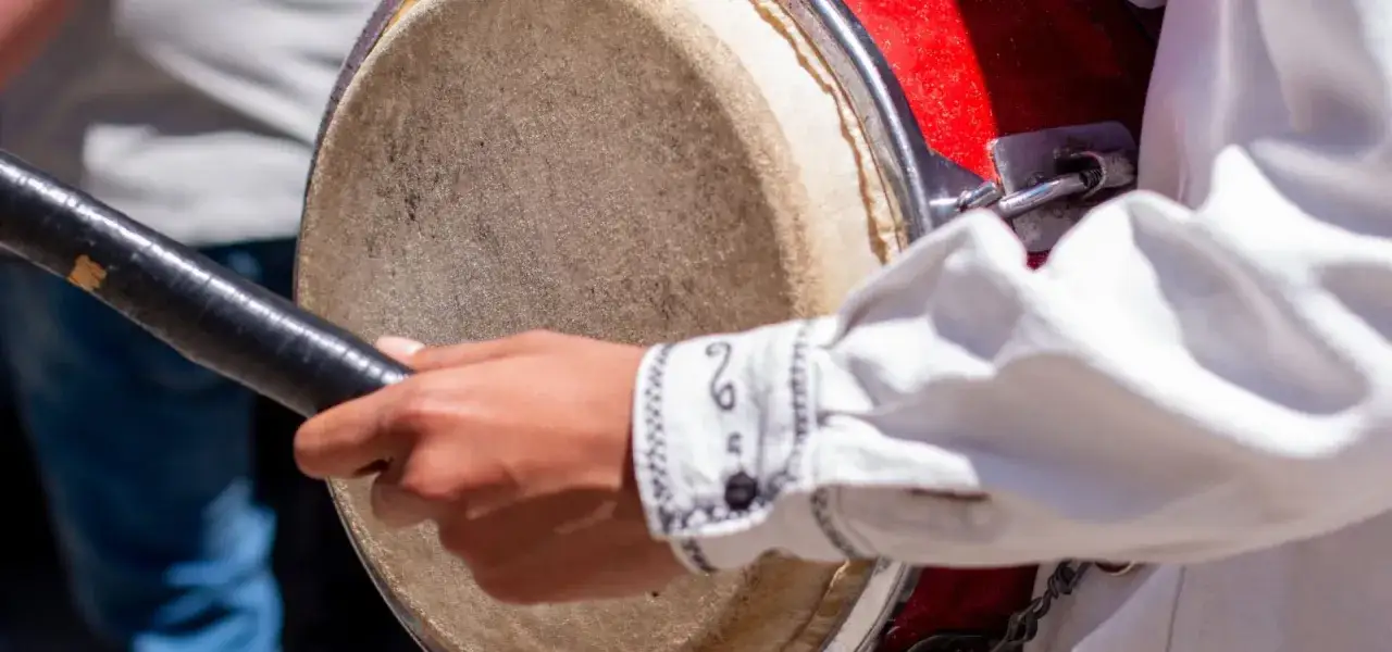 Main d'un musicien frappant un tambour, un instrument traditionnel aux riches ornements.