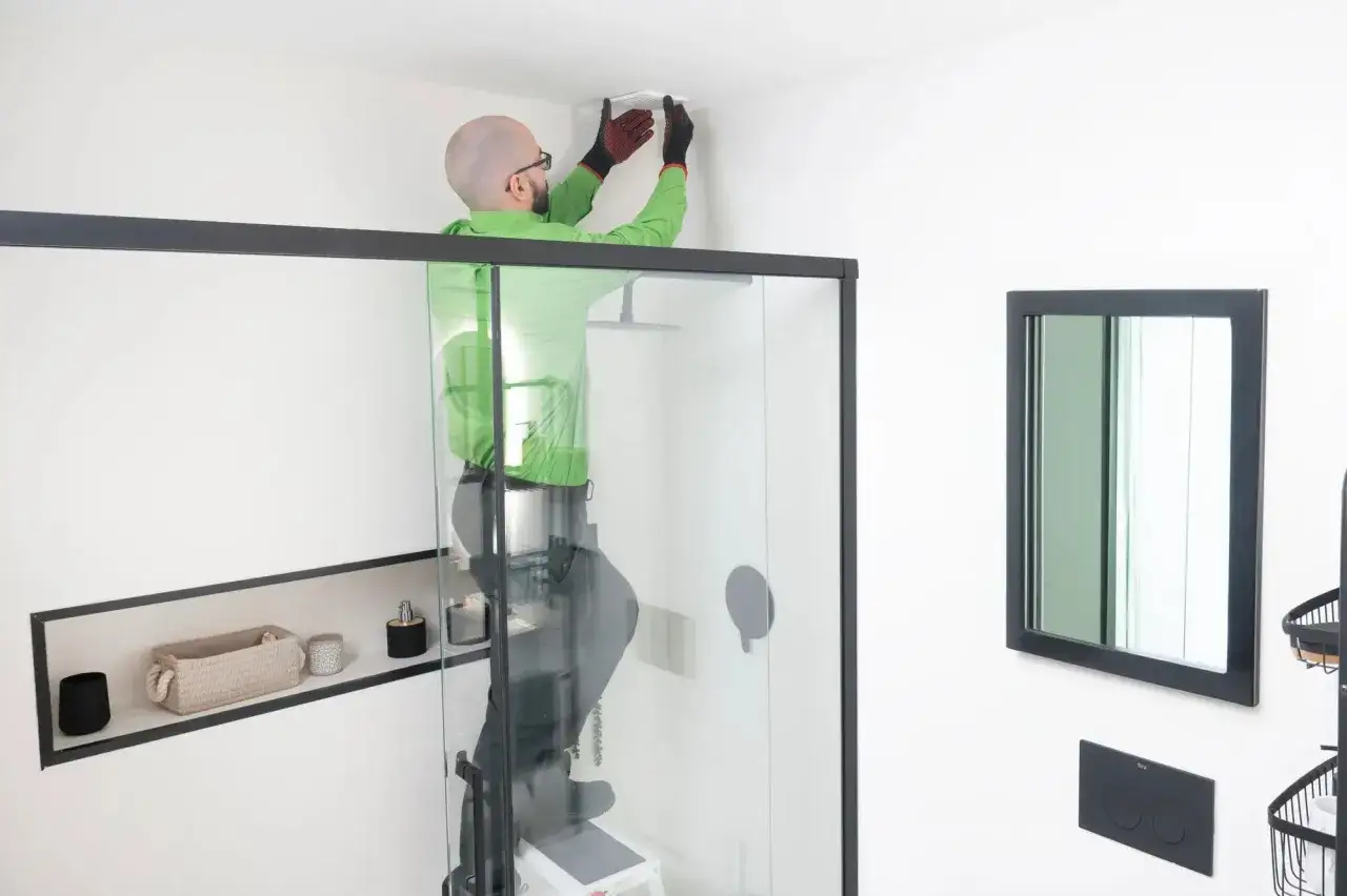 Instalador trabajando en la ventilaci&oacute;n del ba&ntilde;o, asegurando un ambiente fresco y seco.