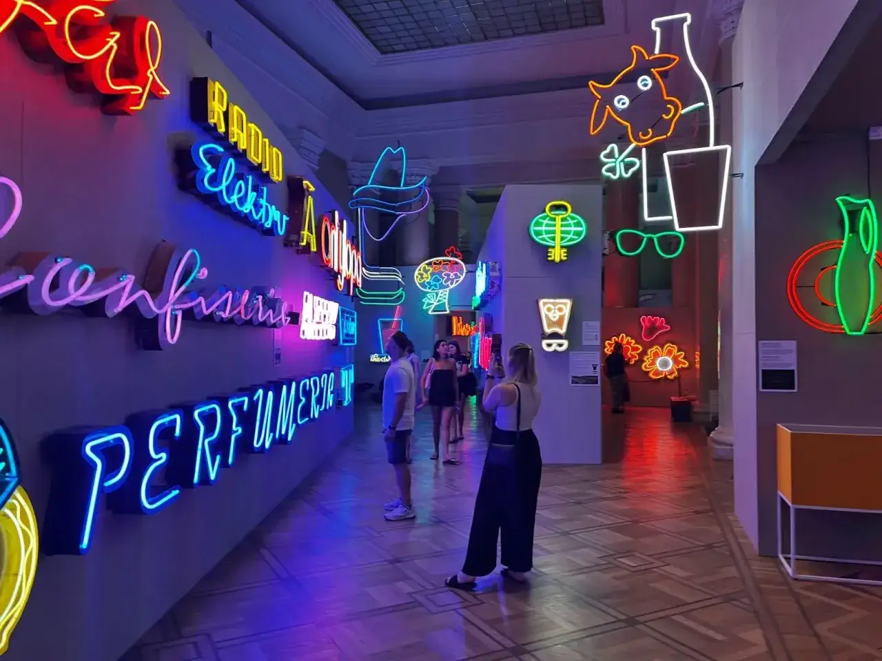 Wystawa neonów w Muzeum Neonów w Warszawie. Kolorowe napisy i grafiki rozświetlają wnętrze, tworząc magiczną atmosferę.
