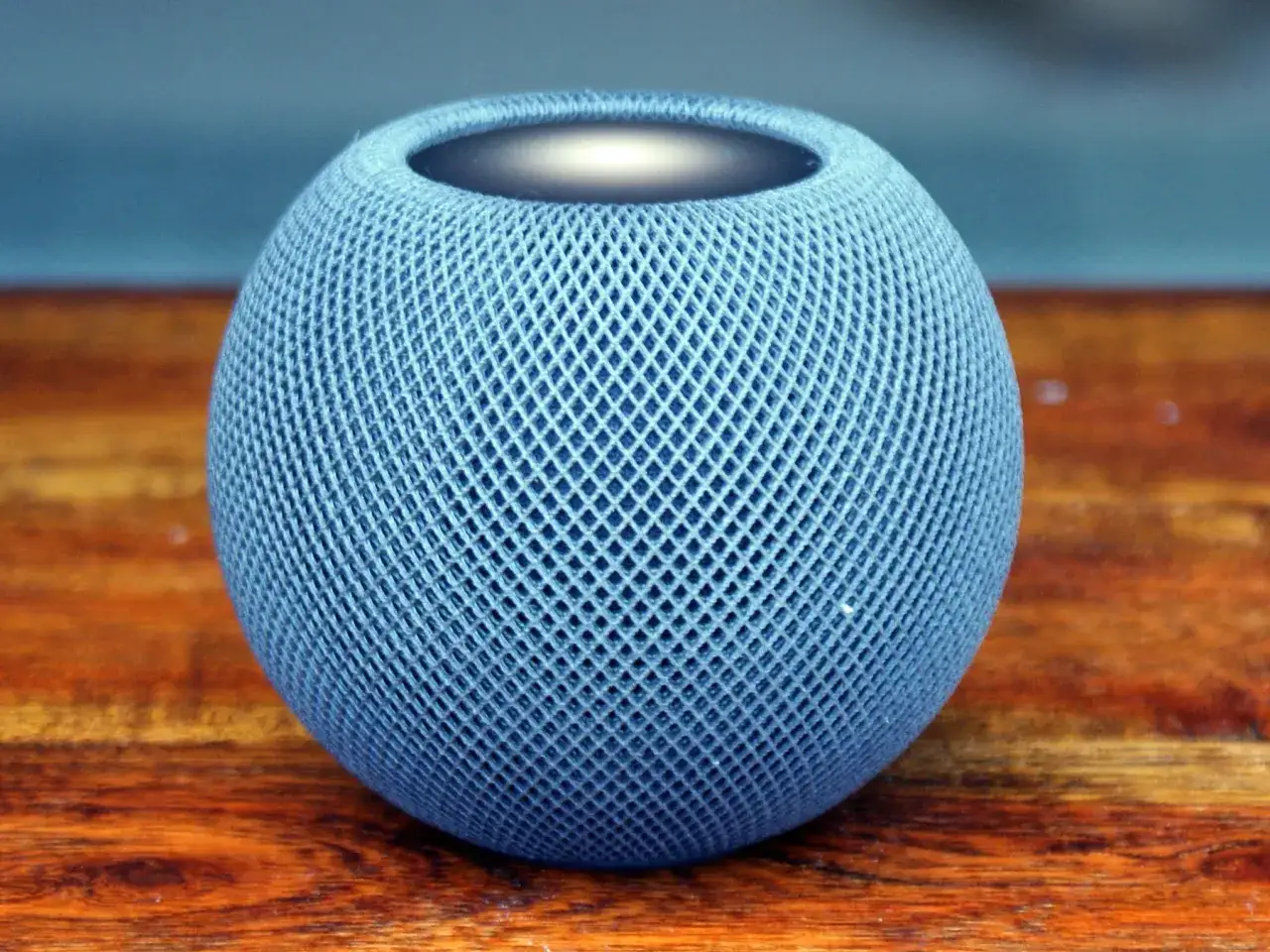 En bl&aring; Apple HomePod mini p&aring; ett tr&auml;bord. En perfekt liten h&ouml;gtalare f&ouml;r ett hem.