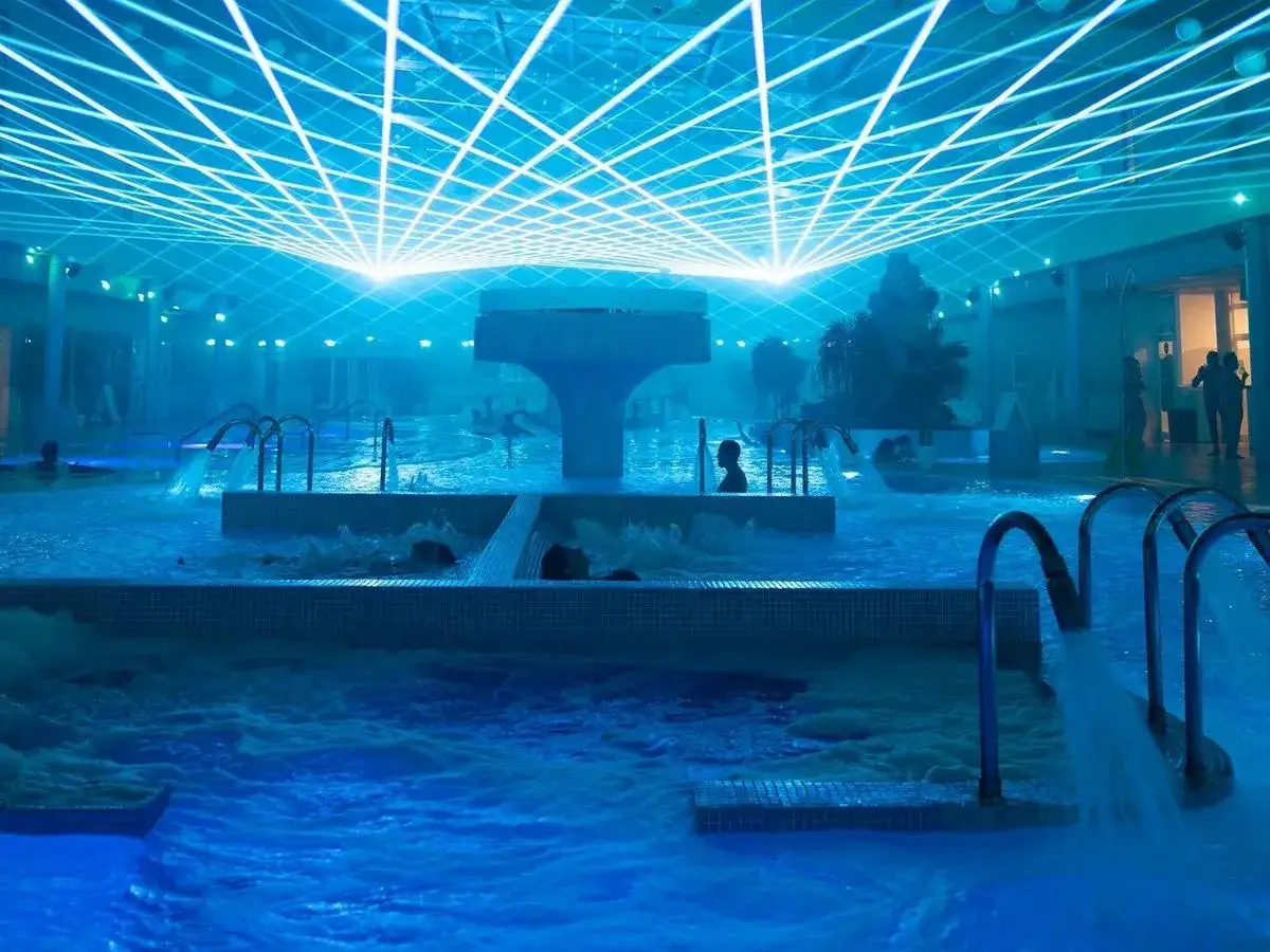 Un relajante spa urbano con piscinas de agua azul, cascadas y una impresionante iluminaci&oacute;n de techo que crea un ambiente futurista.