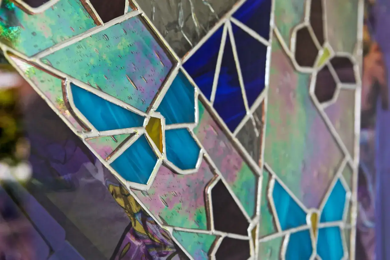 Un vitrail sur mesure aux couleurs iridescentes et bleues, orn&eacute; de motifs de papillons.