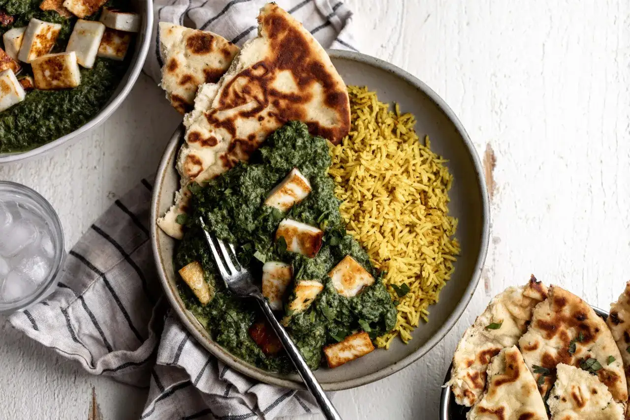 En sk&aring;l med kr&auml;mig palak paneer, gyllene ris och naanbr&ouml;d. Ett perfekt palak paneer recept f&ouml;r en smakrik m&aring;ltid.
