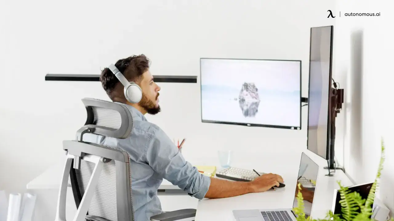 Homme concentré devant deux écrans, casque sur les oreilles, pour éviter la tension oculaire et le stress.