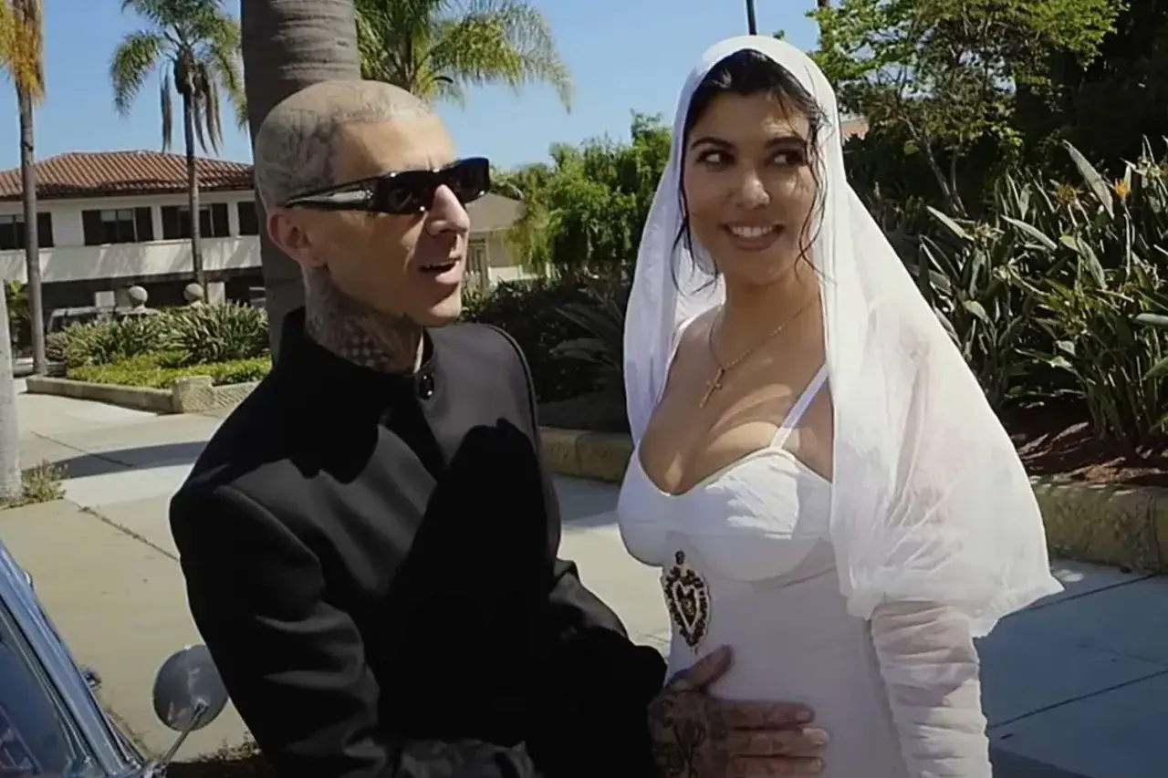 Travis Barker i jego żona Kourtney w dniu ślubu. Ona w białej sukni i welonie, on w czarnym garniturze.