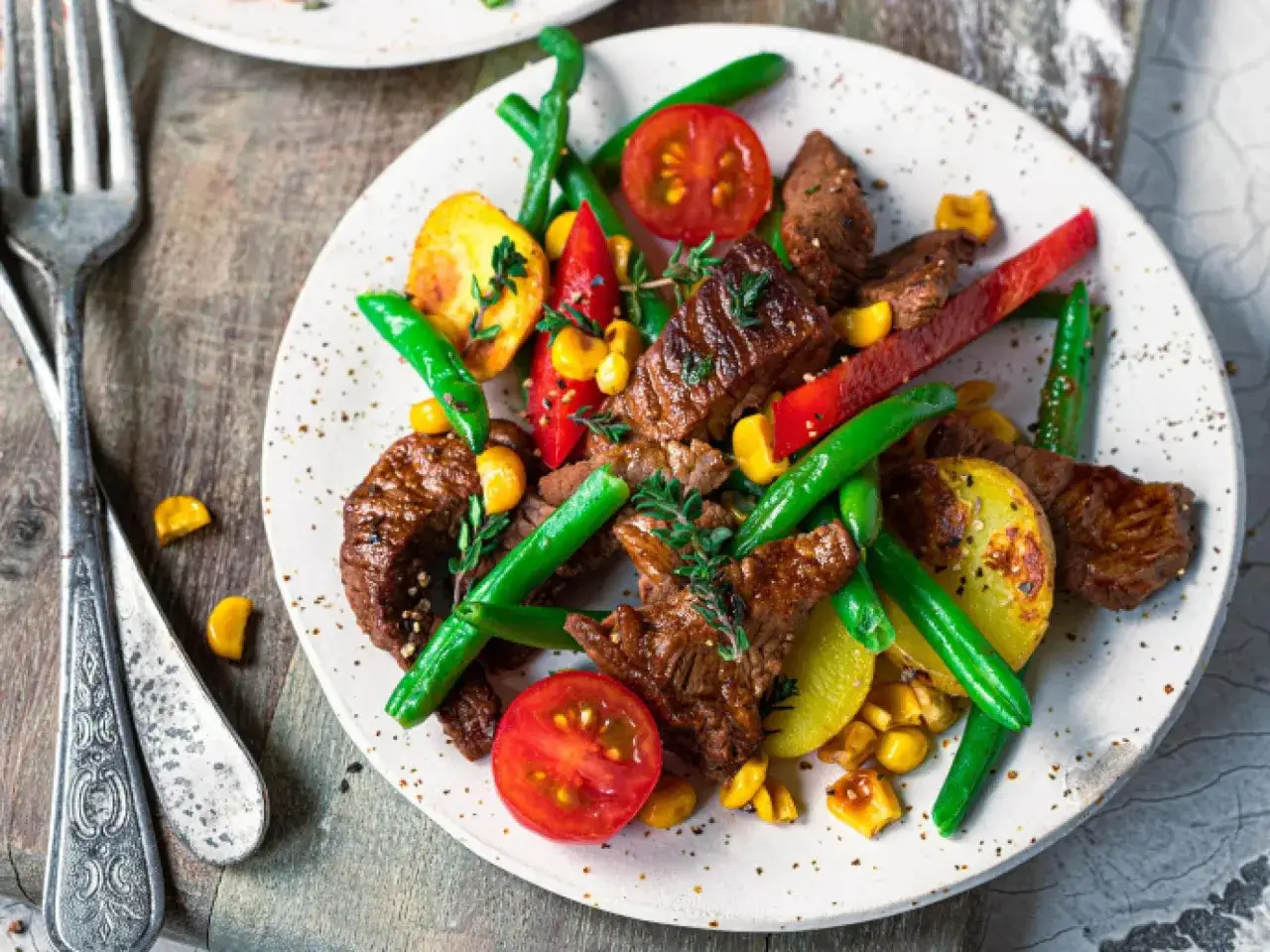 Omas Sonntagsessen: saftiges Rindersteak mit Bratkartoffeln, grünen Bohnen, Mais, Tomaten und Paprika. Ein Festmahl!