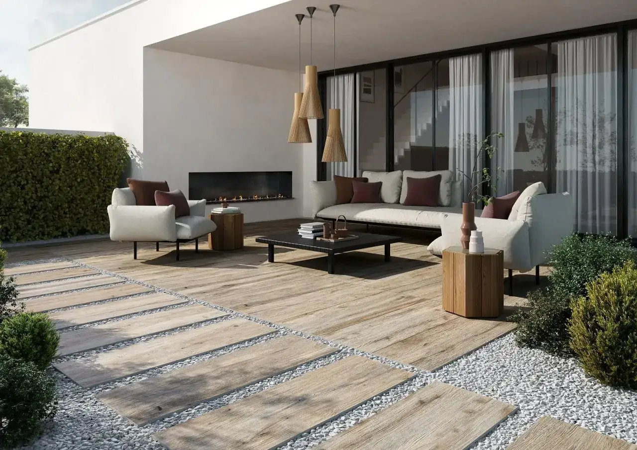 Un elegante terrazzo con un camino moderno, divani accoglienti e un pavimento effetto legno che ricorda il **pavimento casa mare**.