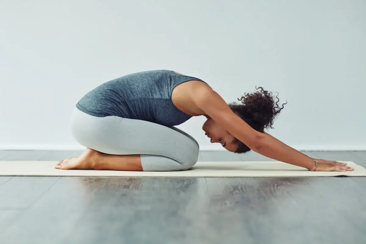 Frau in Kindhaltung auf Yogamatte, eine sanfte Dehnung, die bei Ischias Schmerzen Linderung verschafft.