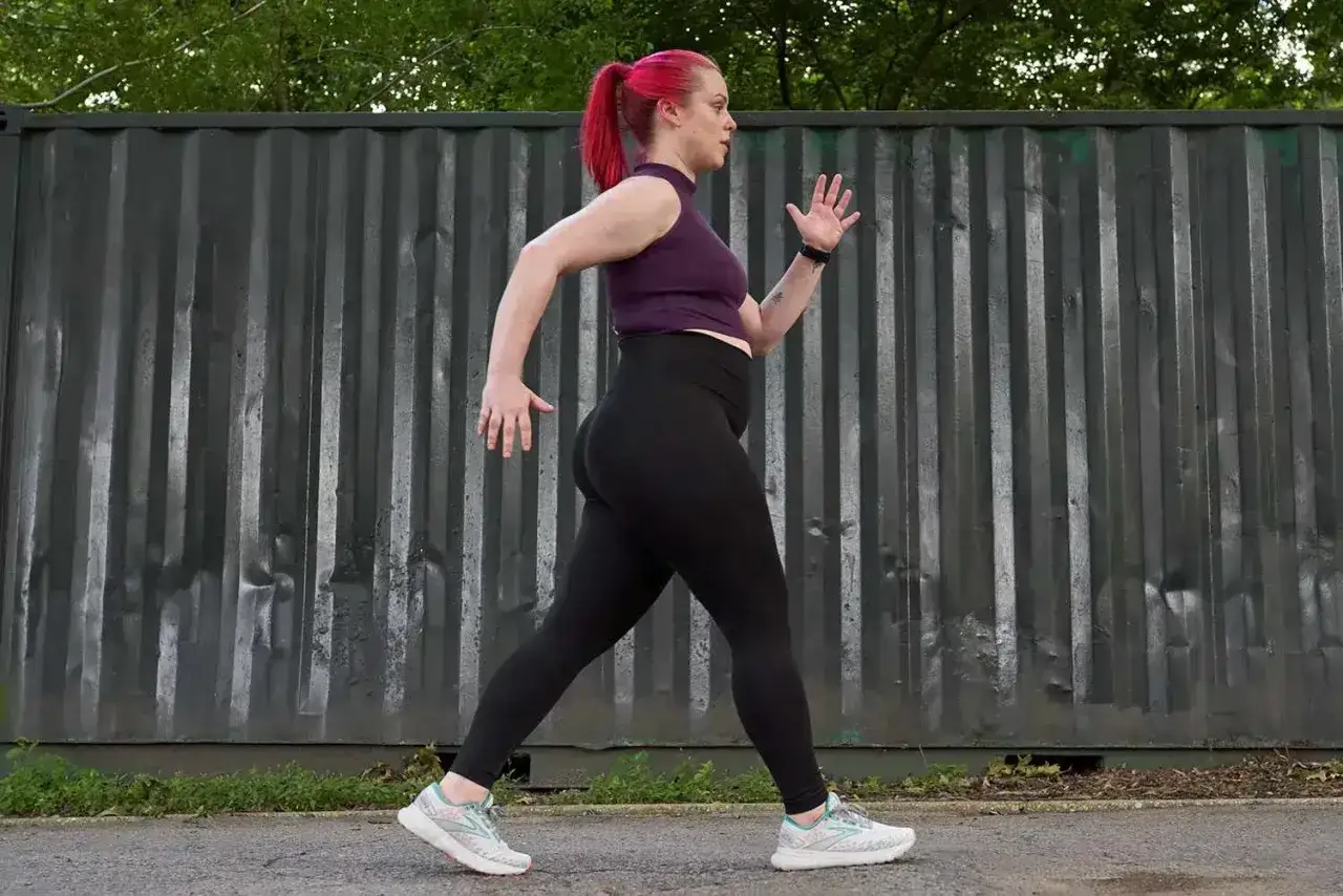 Kobieta z różowymi włosami w sportowym stroju wykonuje speed hiking.