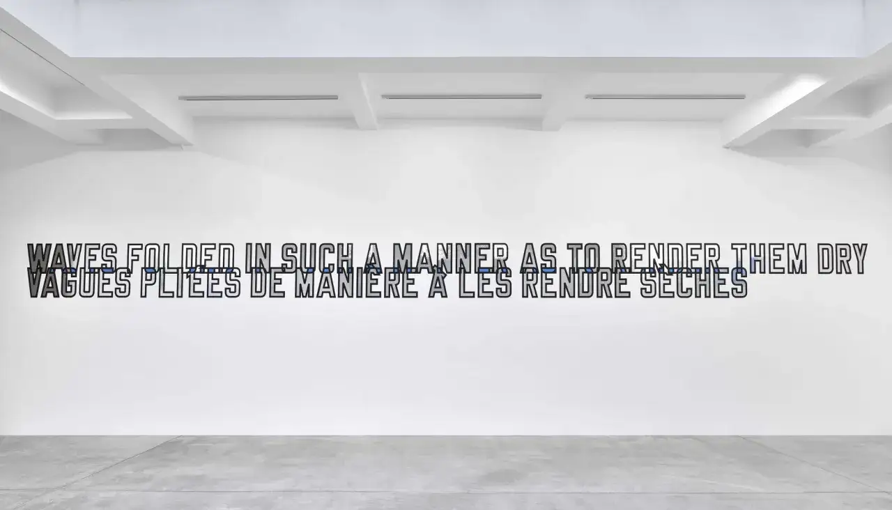Une installation de Lawrence Weiner dans une galerie blanche, avec le texte 