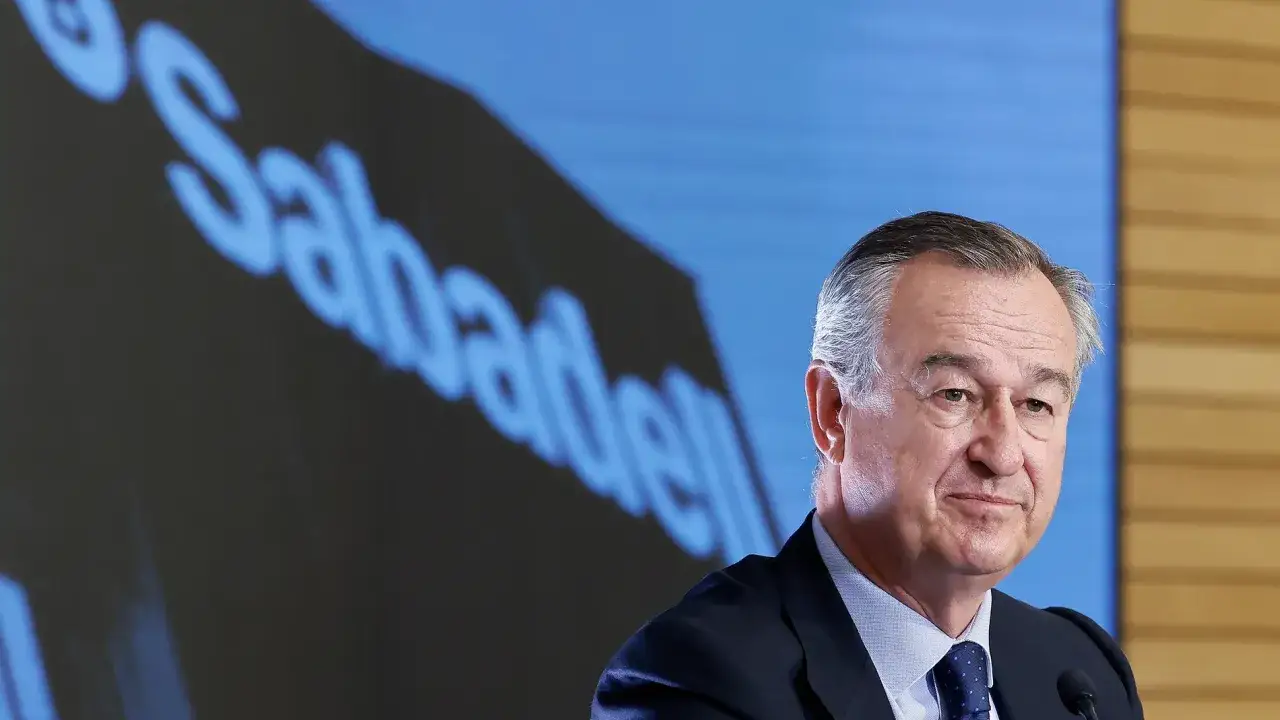 Hombre de traje sonríe ante pantalla con logo de Banco Sabadell. Reseñas positivas sobre la entidad.
