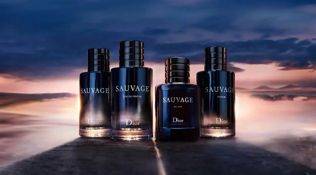 Cztery flakony perfum Christian Dior Sauvage na tle zachodzącego słońca.