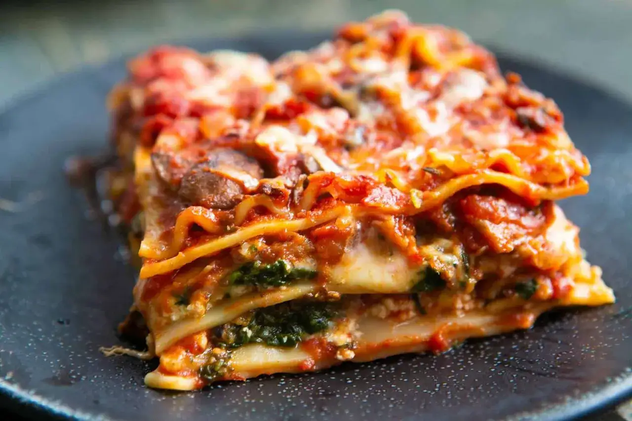 Une part généreuse de lasagne végétarienne, avec ses couches de pâtes, de sauce tomate, de fromage fondant et d'épinards frais.