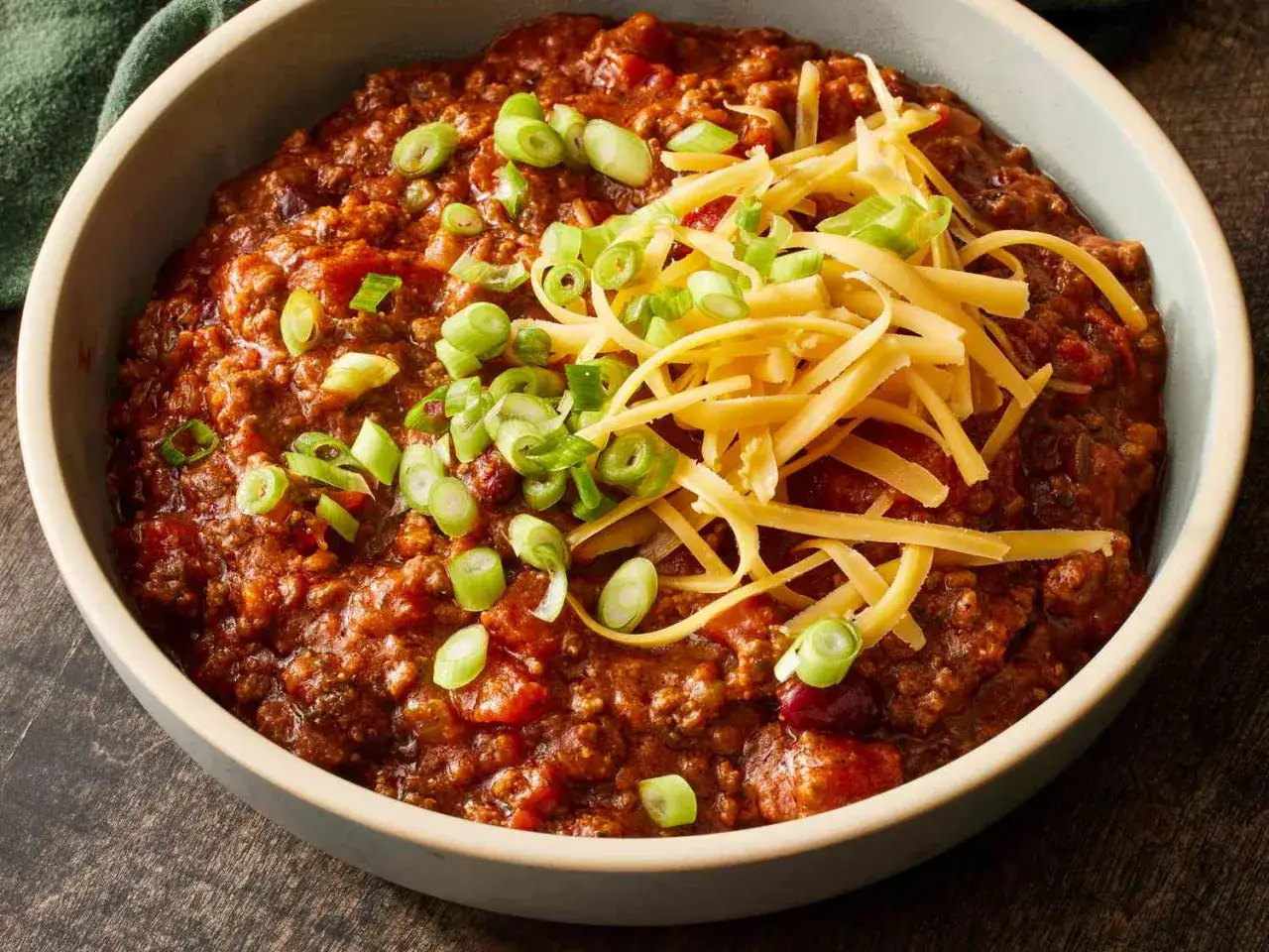 Un bol de chili con carne, garni de fromage r&acirc;p&eacute; et d'oignons verts. Une recette de chef qui r&eacute;chauffe le c&oelig;ur.