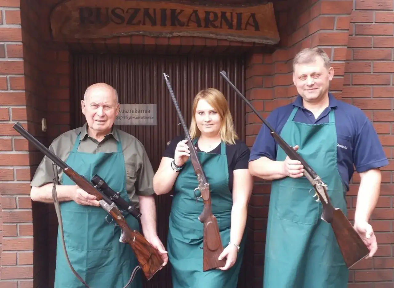 Trzech pracownik&oacute;w zakładu rusznikarskiego pozuje z bronią.