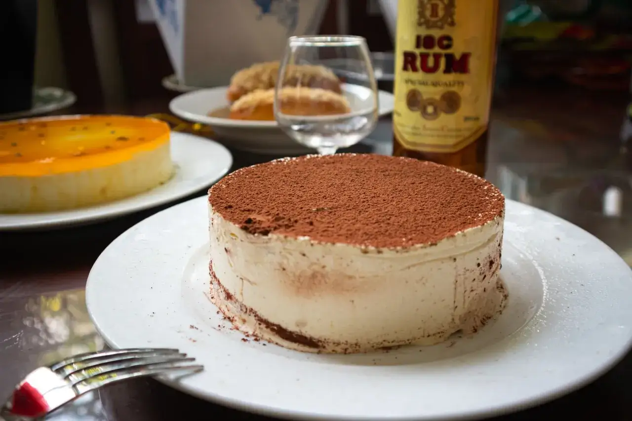 En krämig tiramisu toppad med kakao, redo att avnjutas med en skvätt rom som dryck till tiramisu.