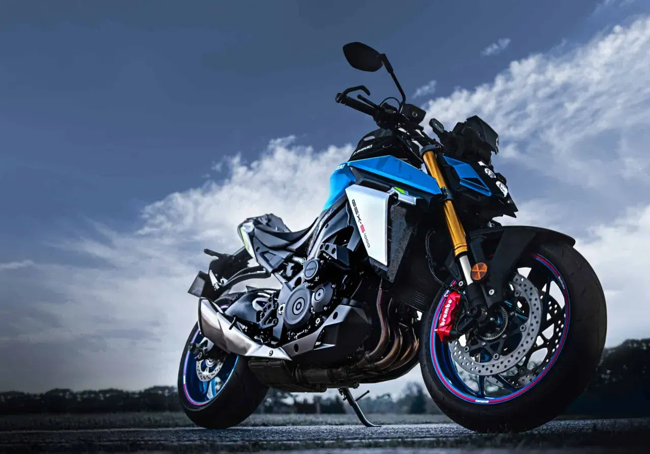 Niebieski motocykl Suzuki GSX-S1000 z czerwonymi zaciskami hamulcowymi Brembo na tle burzowego nieba.