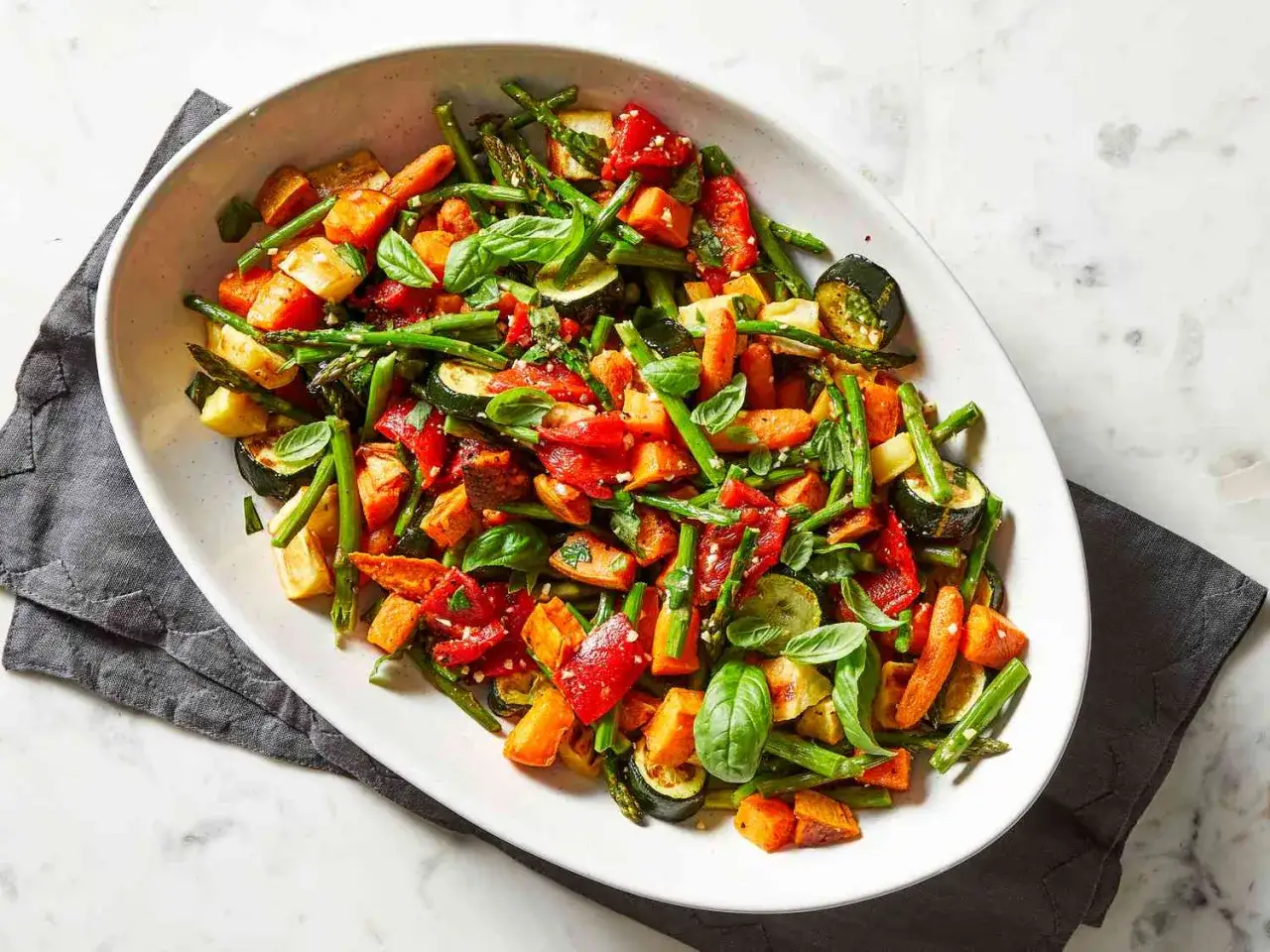 Verduras asadas al horno: calabacín, zanahoria, pimiento rojo y espárragos, con albahaca fresca. El tiempo y temperatura perfectos para un plato saludable.