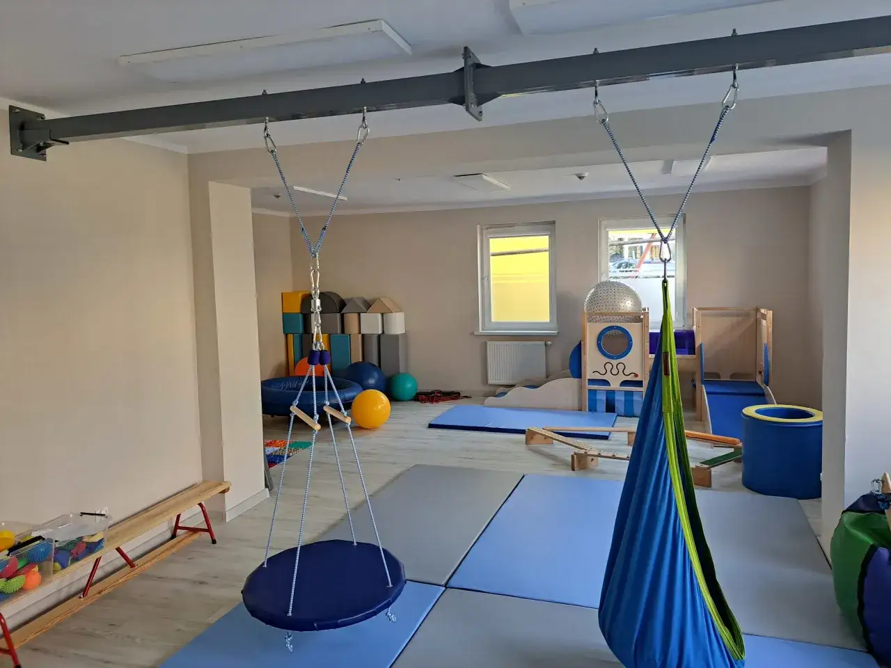 Sala do integracji sensorycznej co to? Huśtawki, materace, piłki i inne pomoce terapeutyczne tworzą przestrzeń do rozwoju.