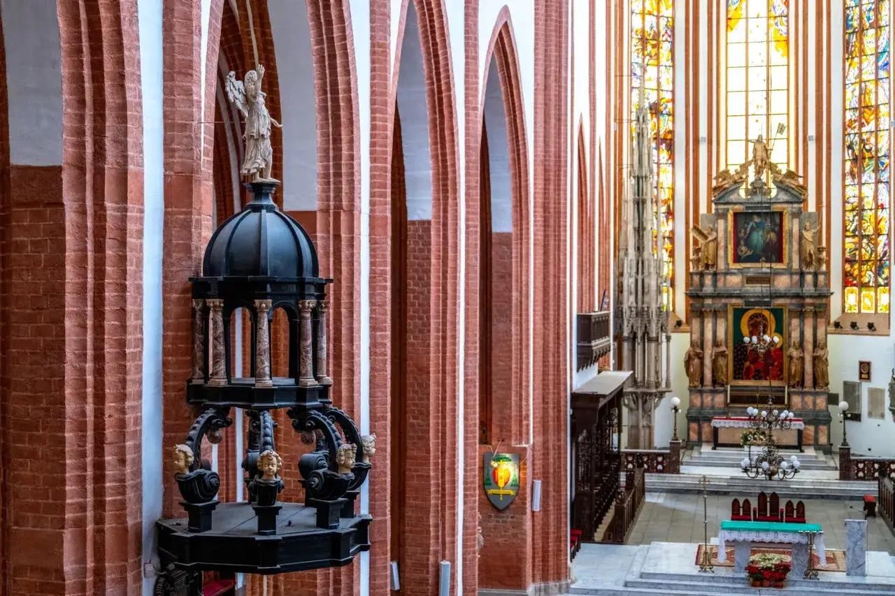 Wnętrze kościoła garnizonowego we Wrocławiu. Widok na ołtarz główny, witraże i zabytkową ambonę z aniołem.