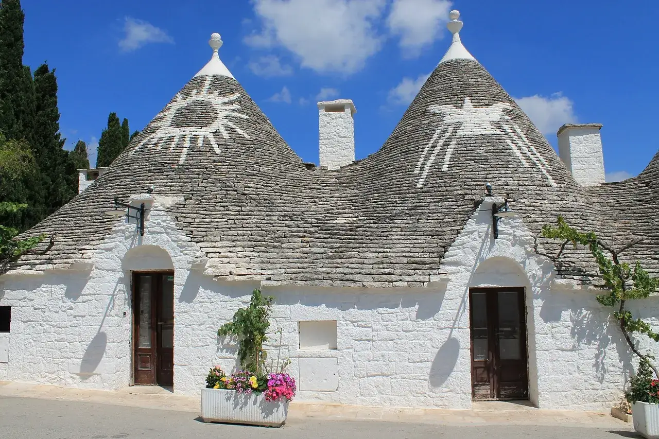 Trulli bianchi con simboli solari, un'immagine iconica dei paesi da visitare in Puglia.