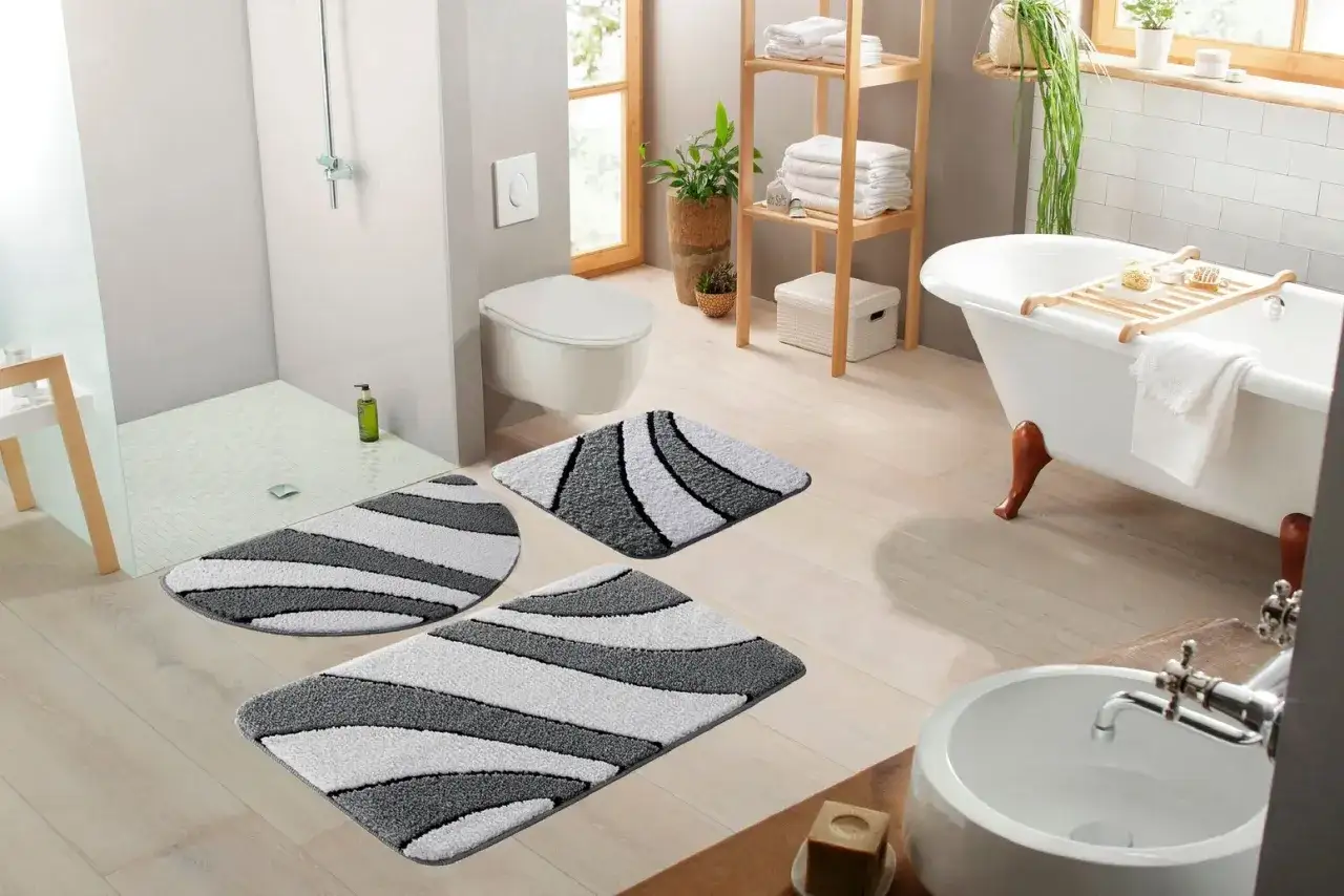 Stilvolle Badtextilien mit Wellenmuster in Grau und Weiß schmücken das Badezimmer neben Dusche, Toilette und Badewanne.