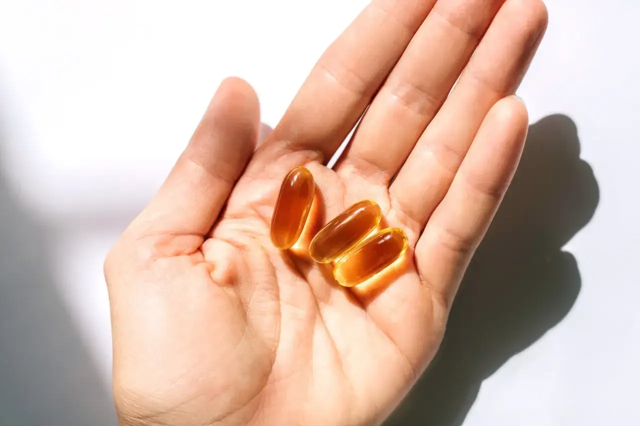 Trzy kapsułki omega-3 zarejestrowane jako lek pan tabletka, leżące na dłoni.