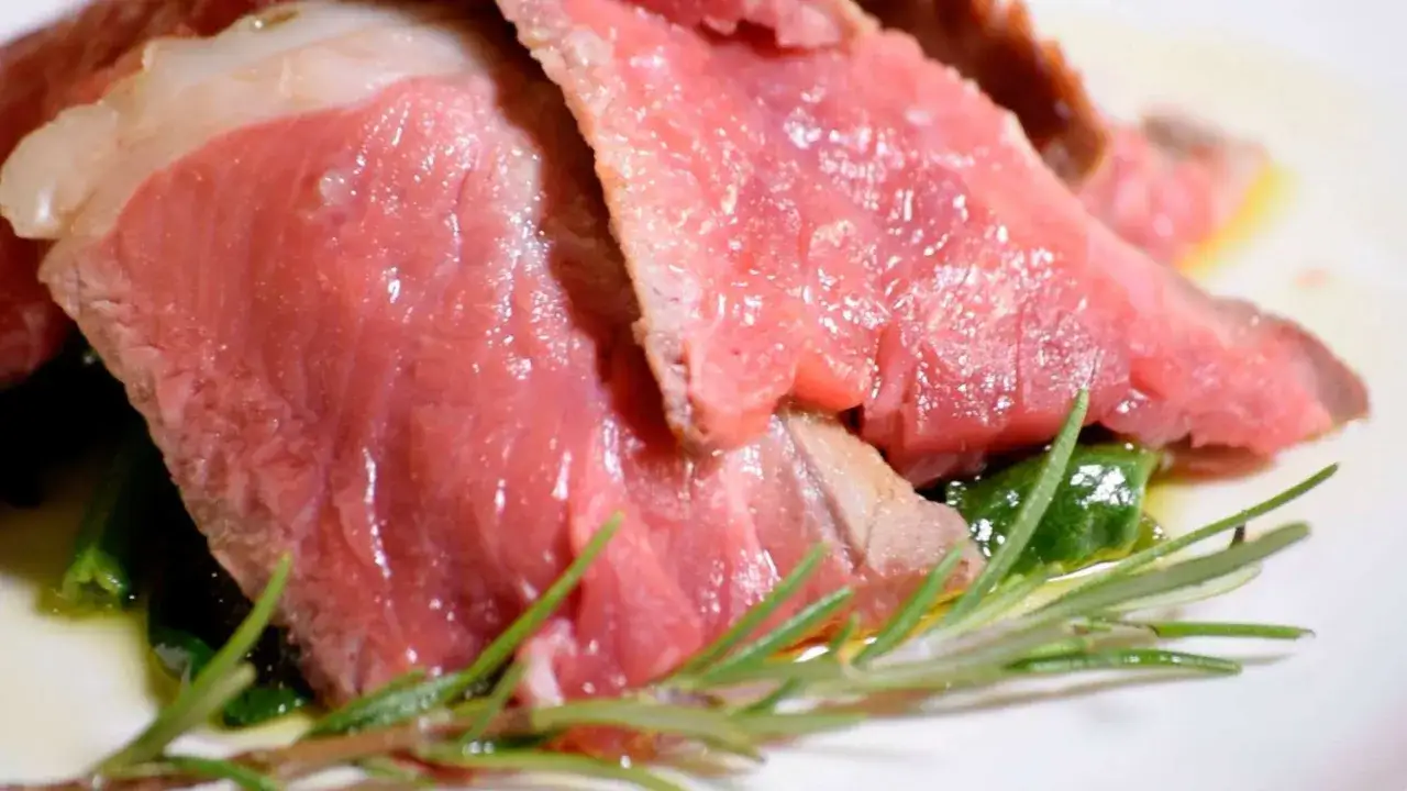 Fette di succulenta bistecca alla fiorentina, un classico della cucina toscana, con rosmarino fresco. La sua storia &egrave; un viaggio nel gusto.