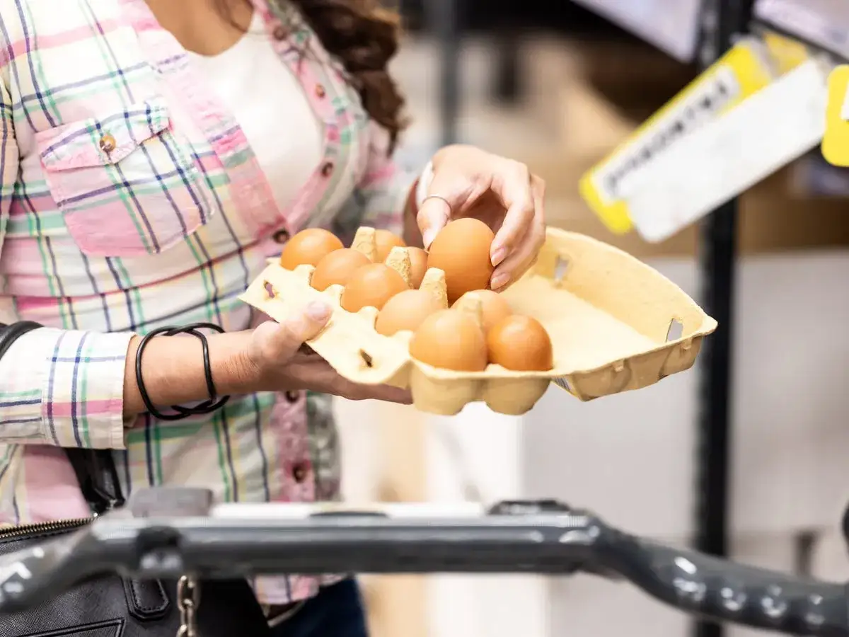 Donna sceglie uova, un'ottima fonte di cibi proteici, in un supermercato.