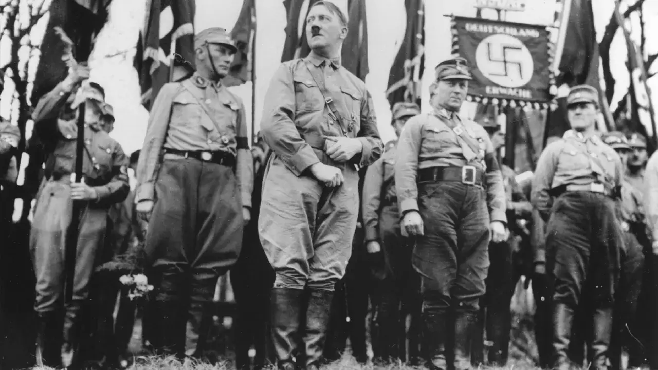 Adolf Hitler y oficiales nazis, con banderas al fondo, evocan la atm&oacute;sfera de la noche de los cuchillos largos.
