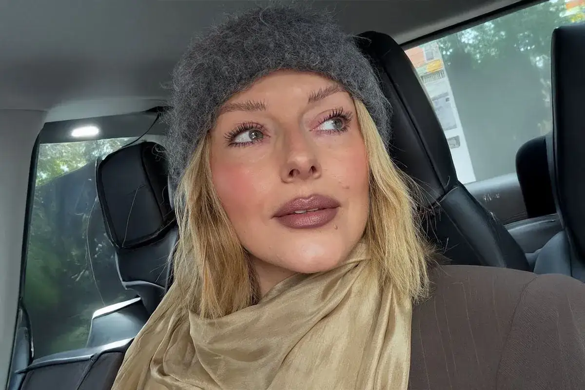 En kvinna i bil med en gr&aring; m&ouml;ssa och en beige scarf. Hennes smink rutin ger henne en fr&auml;sch look.