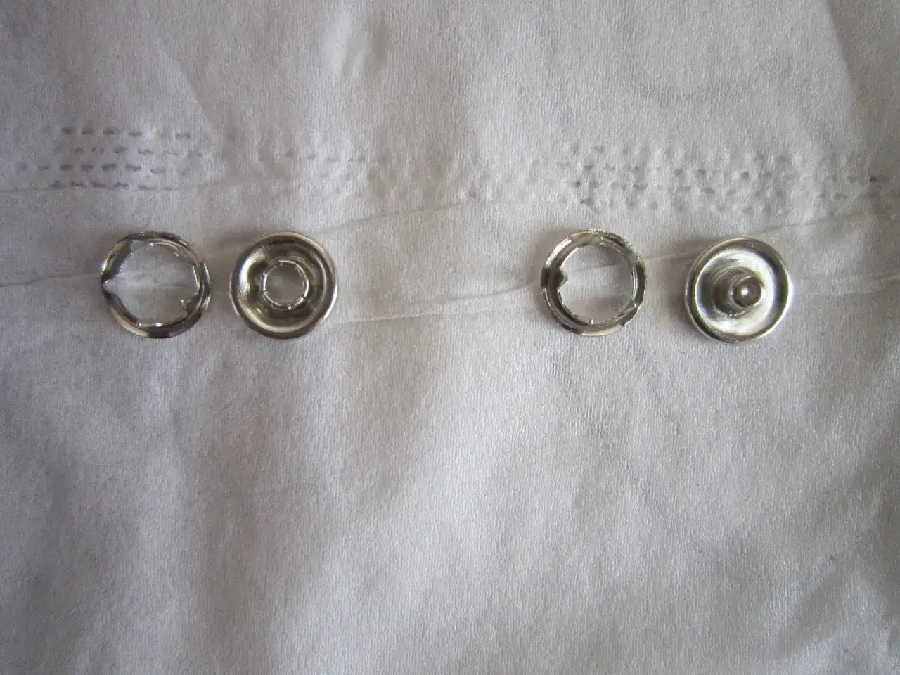Quatre pièces de bouton pression métal, prêtes à poser sans pince.