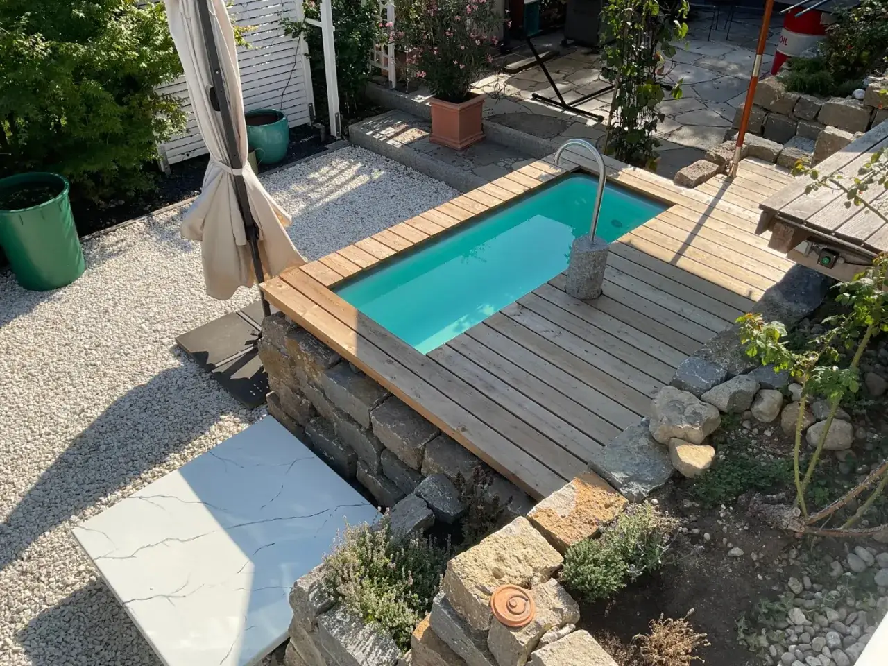 Kleiner Pool mit Holzdeck und Steinmauer. Tolle GFK Erfahrungen f&uuml;r den Garten.