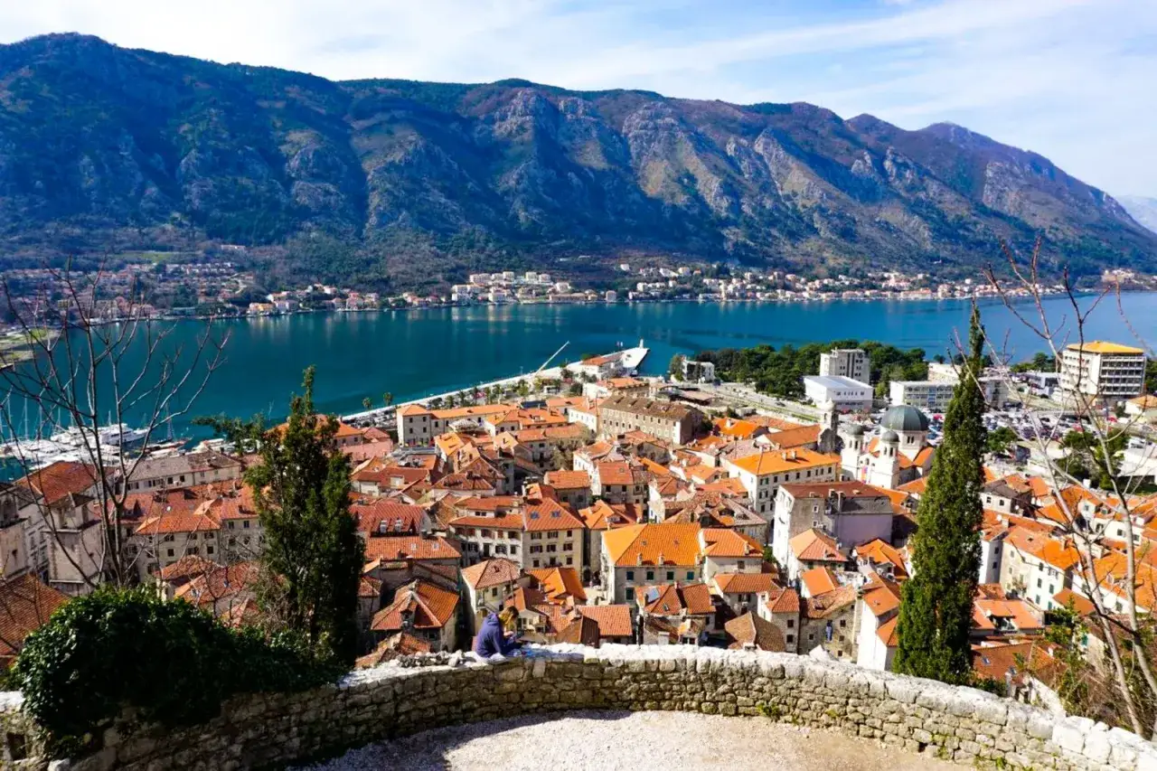 Widok na zabytkowe miasto Kotor w Czarnogórze, z czerwonymi dachami i zatoką otoczoną górami.