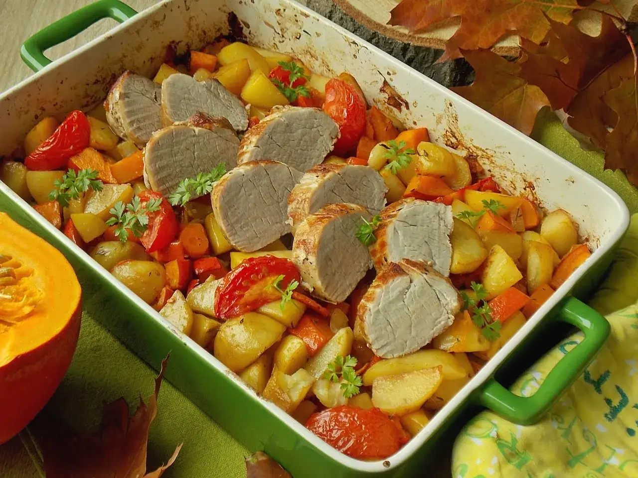 Pieczone polędwiczki wieprzowe z warzywami, okraszone świeżą natką pietruszki. Danie wygląda apetycznie i jesiennie.