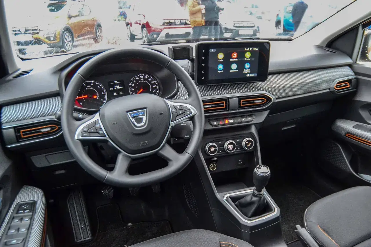 Wnętrze Dacia Sandero Stepway: kierownica, ekran multimedialny, panel klimatyzacji i dźwignia zmiany biegów. Widok na desce rozdzielczej.