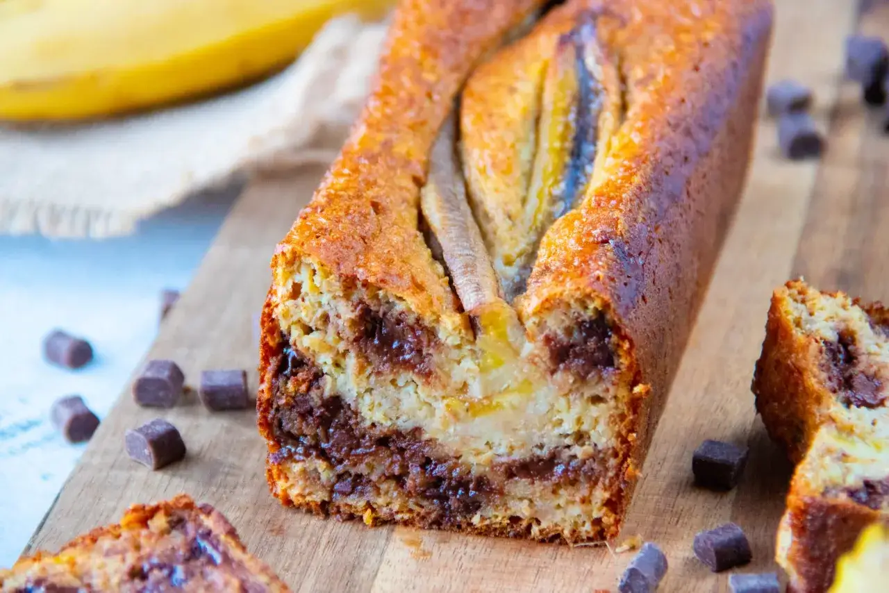 Gâteau banane sans sucre, moelleux et gourmand, avec des morceaux de chocolat et des bananes sur le dessus.