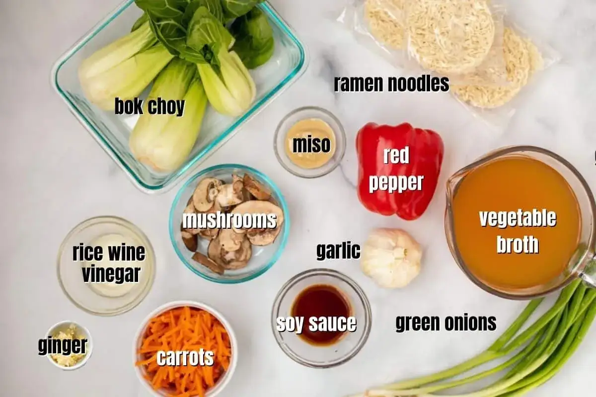 Zutaten f&uuml;r selbstgemachtes Ramen: Bok Choy, Pilze, Karotten, Miso, Sojasauce, Ingwer, Knoblauch, Reisweinessig, rote Paprika, Gem&uuml;sebr&uuml;he und Ramen-Nudeln.
