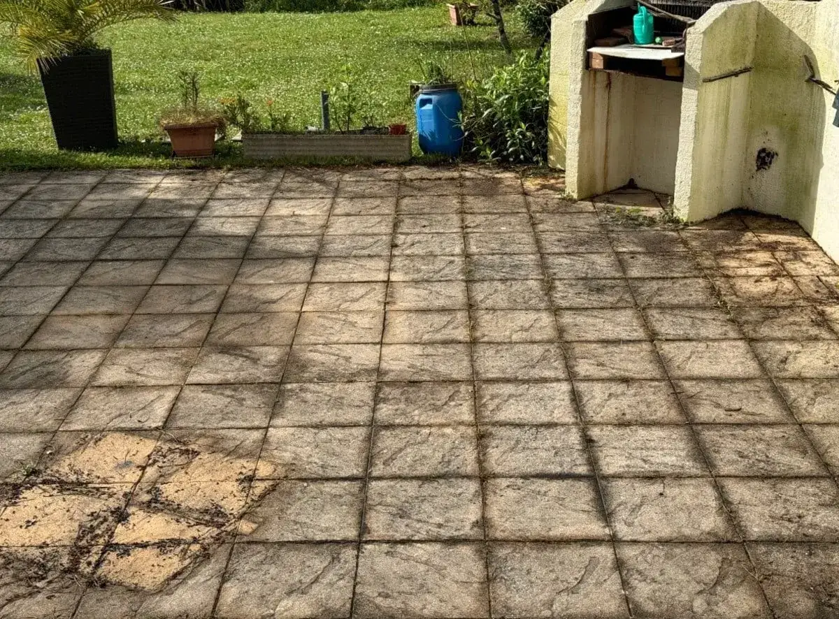 Terrasse en dalles grises, un peu sales, avec un barbecue en pierre &agrave; droite. Le nettoyage dalle terrasse s'impose.