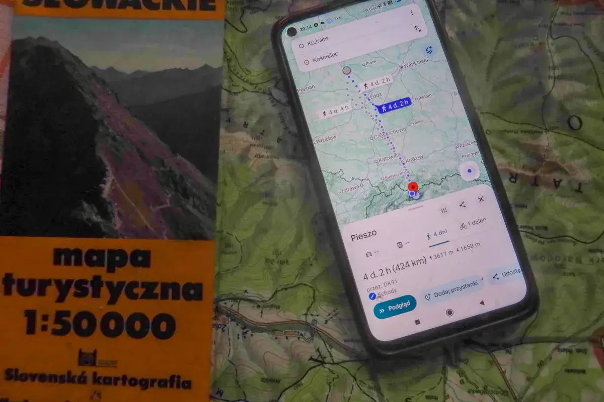 Mapa turystyczna i telefon z nawigacją pokazują trasę pieszą przez góry. Idealny zestaw, by nie zgubić się podczas wędrówki.