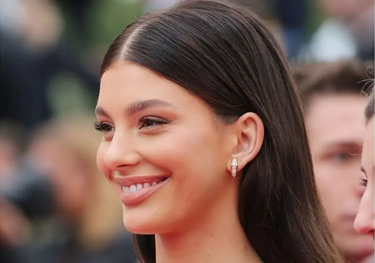 Sonrisa radiante de una mujer con cabello oscuro y liso, luciendo un elegante pendiente.