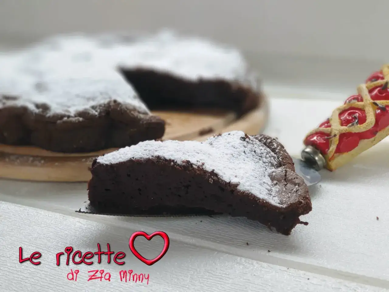 Una fetta di torta tenerina Bimby, soffice e al cioccolato, cosparsa di zucchero a velo.