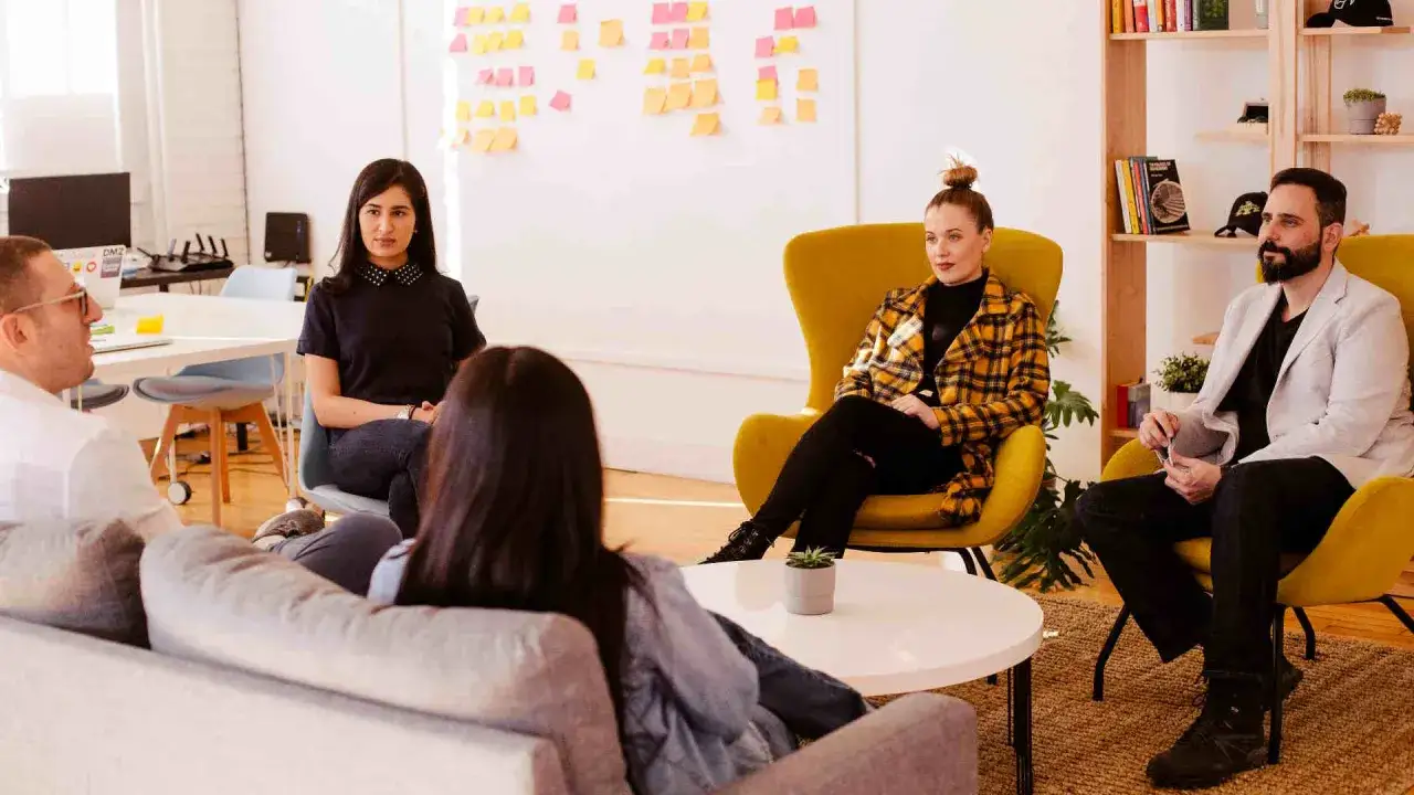 Een team bespreekt idee&euml;n in een open kantoorruimte, wat duidt op psychologische veiligheid en open communicatie.