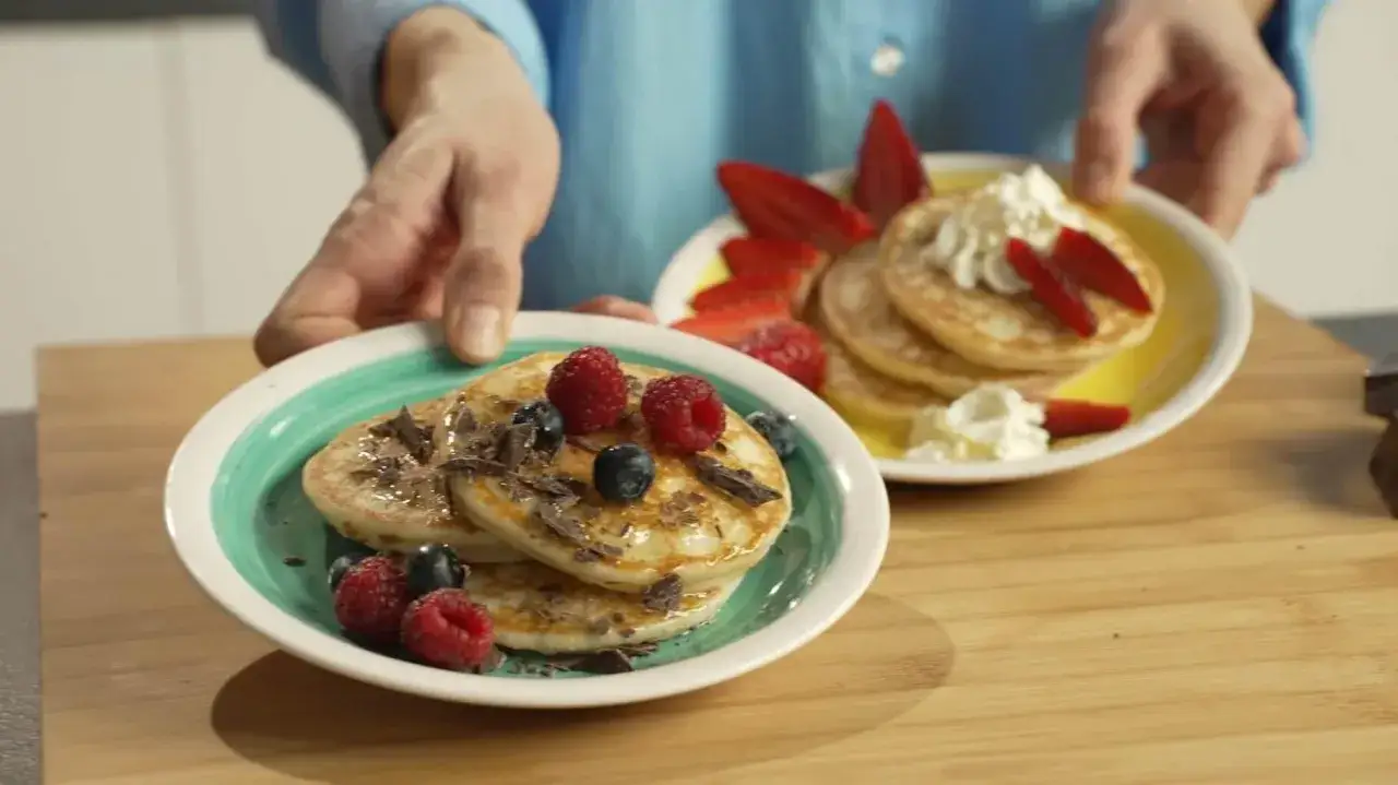Pancake friggitrice ad aria con frutti di bosco e scaglie di cioccolato, serviti su piatti colorati.