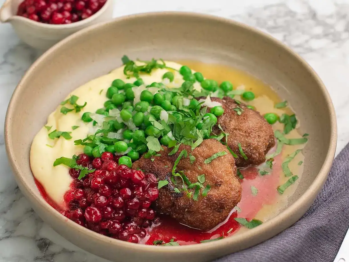 Wallenbergare recept: Krämigt potatismos, ärtor, lingon och två gyllene Wallenbergare i en skål.