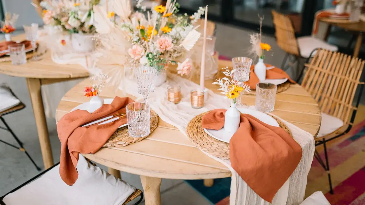 Table dress&eacute;e pour un mariage boh&egrave;me : nappes en lin ocre, fleurs s&eacute;ch&eacute;es, bougies et vaisselle &eacute;l&eacute;gante.