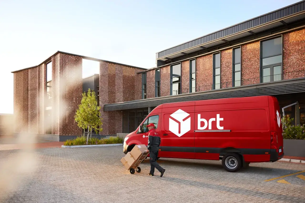 Corriere BRT scarica pacchi da un furgone rosso. Ottime opinioni per chi ama lavorare in Bartolini.
